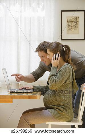 Couple using laptop at home View Large Photo Image Stock Photograph - Couple using laptop at home. Fotosearch