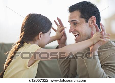 Stock Image - Daughter (8-9) and father playing together. Fotosearch