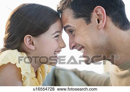 Stock Photo - Daughter (8-9) and father touching foreheads. Fotosearch