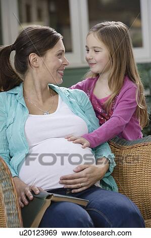 Stock Photo - Expectant mother and daughter (4-5) relaxing. Fotosearch