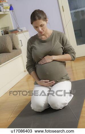 Stock Image - Expectant mother sitting on exercise mat. Fotosearch