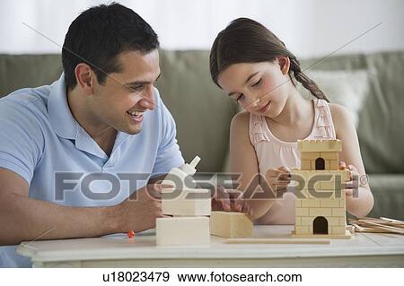 Stock Photo - Father and daughter (8-9) building toy castle. Fotosearch
