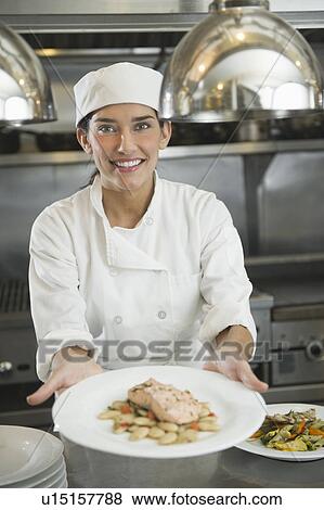 Female cook showing food on plate View Large Photo Image Stock Photo - Female cook showing food on plate. Fotosearch