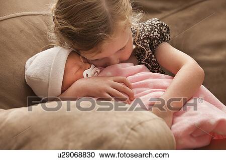 Girl (2-3) embracing baby sister on sofa View Large Photo Image Stock Image - Girl (2-3) embracing baby sister on sofa. Fotosearch