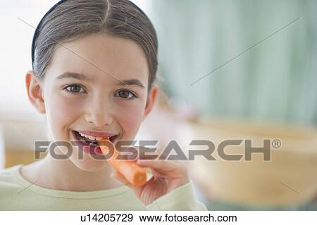Stock Photo - Girl (8-9) eating carrot. Fotosearch