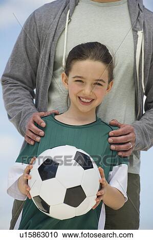 Girl (8-9) holding soccer ball, with father behind View Large Photo Image Stock Image - Girl (8-9) holding soccer ball, with father behind. Fotosearch