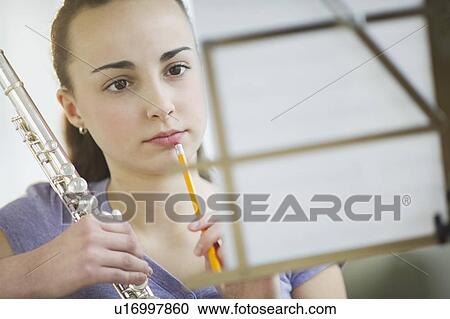 Stock Image - Girl with flute reading sheet music. Fotosearch