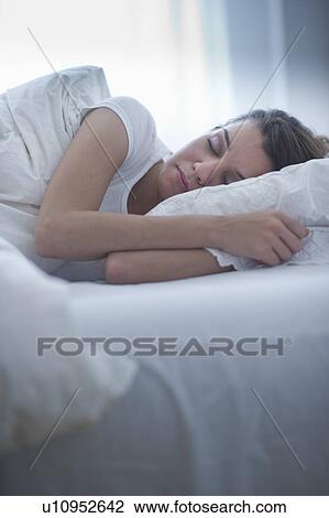 Stock Image - Happy young woman sleeping in bed. Fotosearch