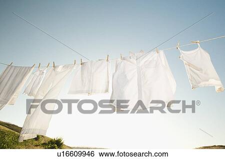 Laundry hanging on clothesline against blue sky View Large Photo Image Stock Photograph - Laundry hanging on clothesline against blue sky. Fotosearch