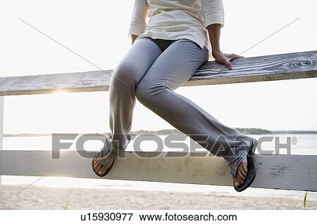 Legs of woman sitting on rail fence, lake in background View Large Photo Image Stock Photo - Legs of woman sitting on rail fence, lake in background. Fotosearch