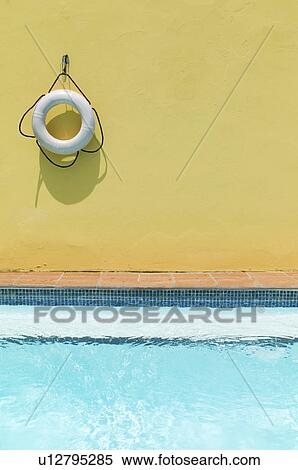 Lifebelt hanging on yellow wall by swimming pool View Large Photo Image Stock Photography - Lifebelt hanging on yellow wall by swimming pool. Fotosearch