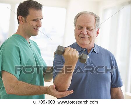Stock Image - Man assisting senior man weight lifting. Fotosearch