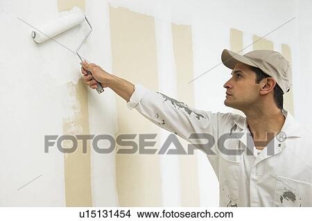 Picture - Man painting wall white. Fotosearch