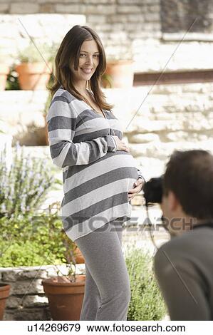 Stock Photo - Man photographing pregnant woman. Fotosearch