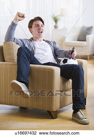 Man sitting in chair and watching TV soccer game View Large Photo Image Stock Image - Man sitting in chair and watching TV soccer game. Fotosearch
