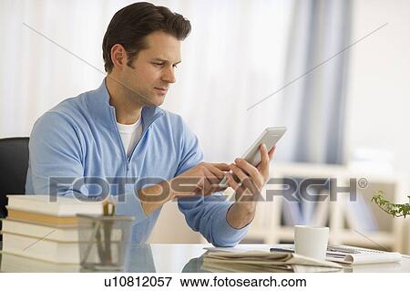 Stock Photo - Man using digital tablet at home office. Fotosearch