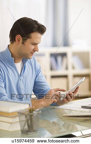 Man using digital tablet at home office View Large Photo Image Stock Photo - Man using digital tablet at home office. Fotosearch