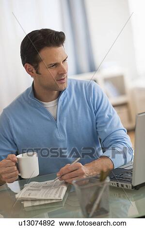 Stock Image - Man using laptop at home office. Fotosearch
