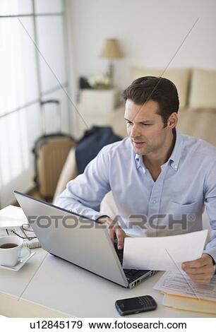 Stock Photo - Man using laptop at home office. Fotosearch