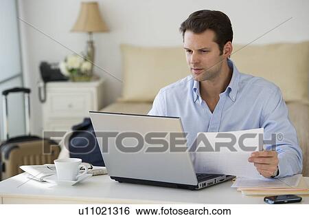 Man using laptop at home office View Large Photo Image Stock Photograph - Man using laptop at home office. Fotosearch