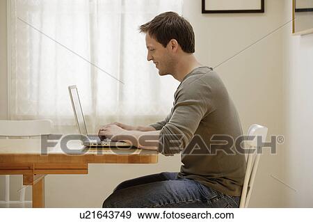 Stock Photo - Man using laptop at home. Fotosearch