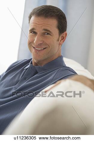 Stock Photography - Mature man sitting on sofa. Fotosearch
