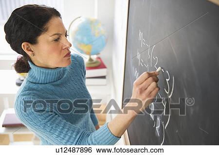 Stock Photograph - Mature woman writing on blackboard. Fotosearch