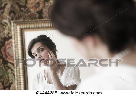 Stock Photography - Old-fashioned young woman looking at mirror reflection. Fotosearch