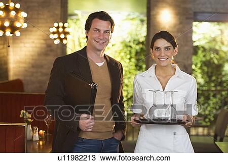 Stock Image - Owner and waitress in restaurant. Fotosearch