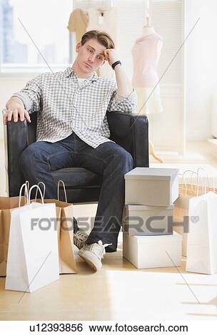 Pensive man sitting in clothes store View Large Photo Image Stock Photograph - Pensive man sitting in clothes store. Fotosearch