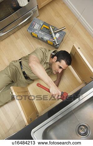 Stock Image - Plumber fixing sink, view from above. Fotosearch