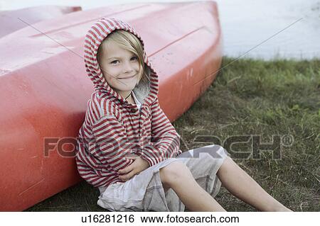 Stock Photograph - Portrait of boy (4-5) sitting by canoe. Fotosearch