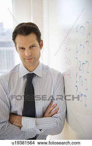 Picture - Portrait of businessman leaning against whiteboard. Fotosearch
