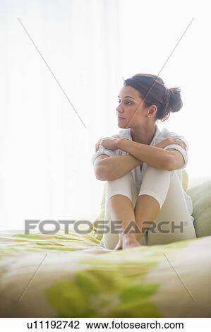 Stock Image - Portrait of cheerful young woman sitting with legs crossed. Fotosearch