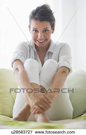 Stock Photo - Portrait of cheerful young woman sitting with legs crossed. Fotosearch