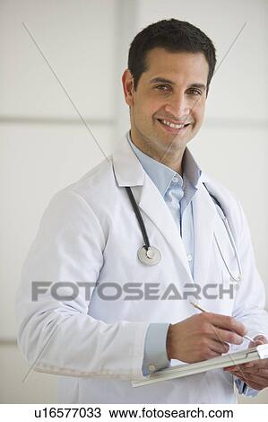 Stock Image - Portrait of doctor writing in notepad. Fotosearch