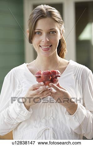 Stock Photo - Portrait of expecting mother eating strawberries. Fotosearch