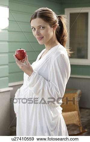 Stock Photo - Portrait of expecting mother eating apple. Fotosearch