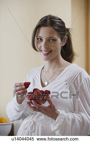Stock Photography - Portrait of expecting mother eating strawberries. Fotosearch