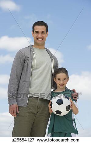 Stock Photo - Portrait of father and daughter (8-9) with soccer ball. Fotosearch