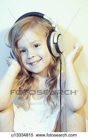 Stock Photography - Portrait of girl (4-5) listening to headphones. Fotosearch