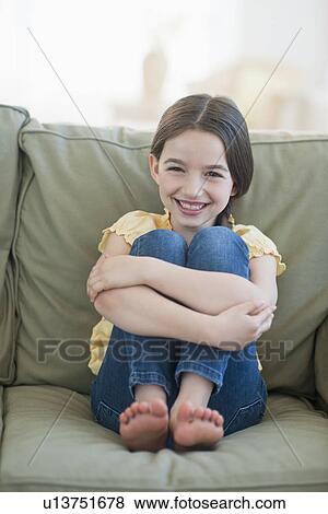 Portrait of girl (8-9) sitting on sofa View Large Photo Image Stock Photo - Portrait of girl (8-9) sitting on sofa. Fotosearch