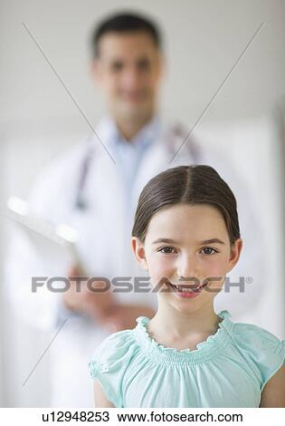 Portrait of girl (8-9), with doctor behind View Large Photo Image Stock Image - Portrait of girl (8-9), with doctor behind. Fotosearch