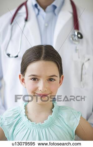 Stock Photography - Portrait of girl (8-9), with doctor behind. Fotosearch