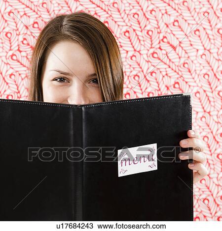 Portrait of smiling young woman holding restaurant menu in front of face View Large Photo Image Stock Image - Portrait of smiling young woman holding restaurant menu in front of face. Fotosearch