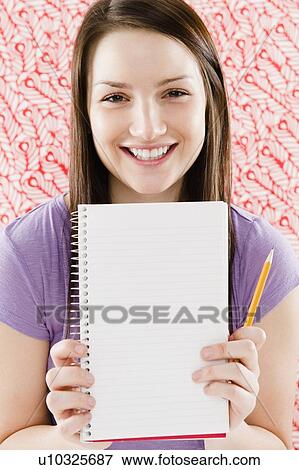 Stock Photo - Portrait of smiling young woman holding blank notebook. Fotosearch