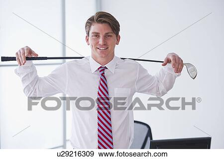 Stock Photo - Portrait of young businessman holding golf club. Fotosearch