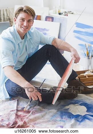 Stock Photography - Portrait of young man painting picture in studio. Fotosearch
