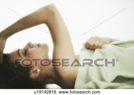 Stock Photograph - Profile of young woman lying in bed . Fotosearch
