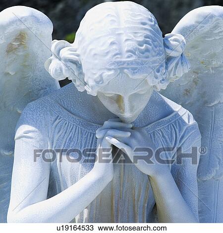 Stock Image - Puerto Rico, Old San Juan, Santa Maria Magdalena Cemetery, Close-up view of praying angel statue. Fotosearch
